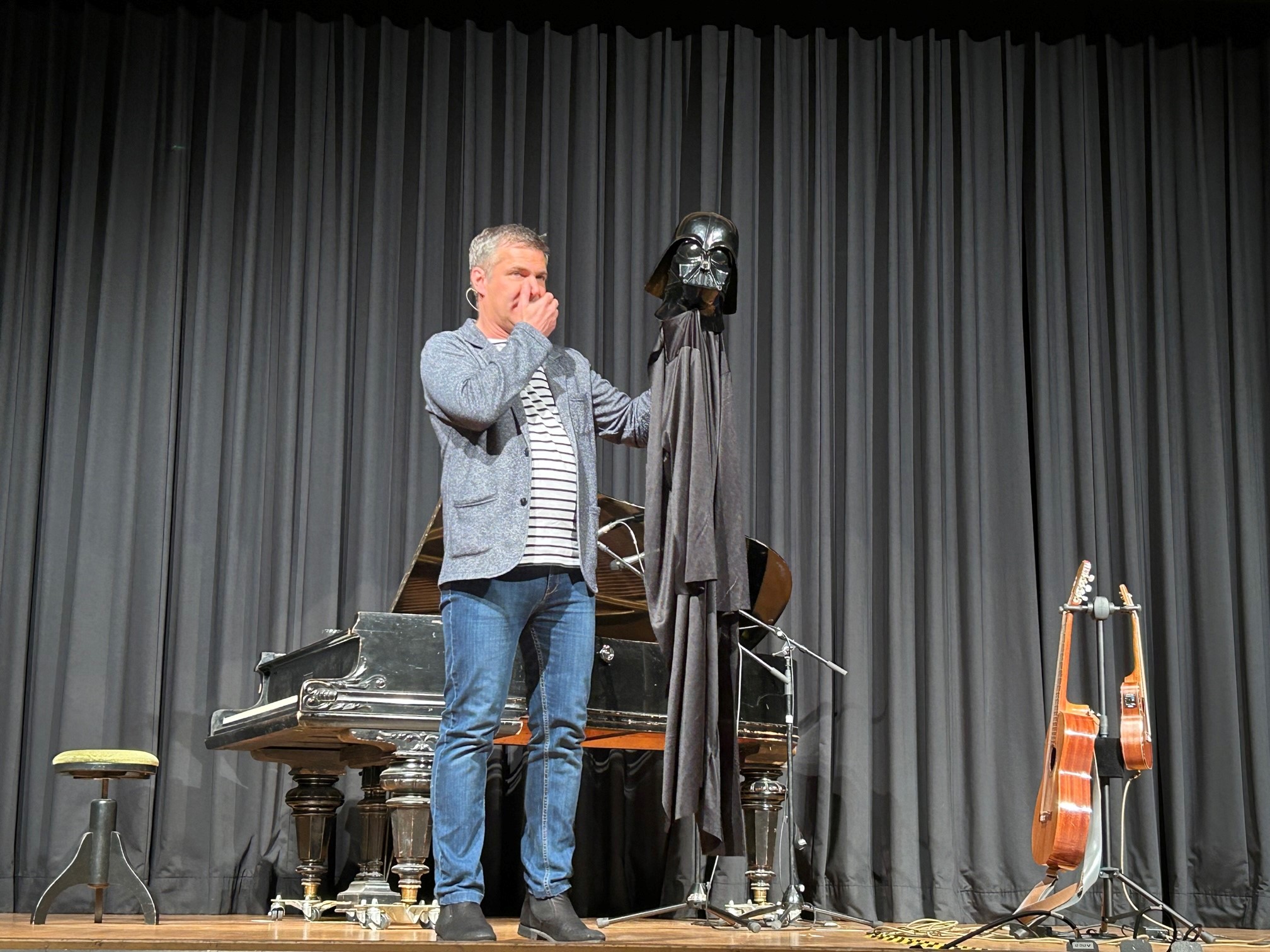 Hier sieht man den Künstler Markus Kapp auf der Bühne mit einem Darth Vader Helmut in der Hand. 