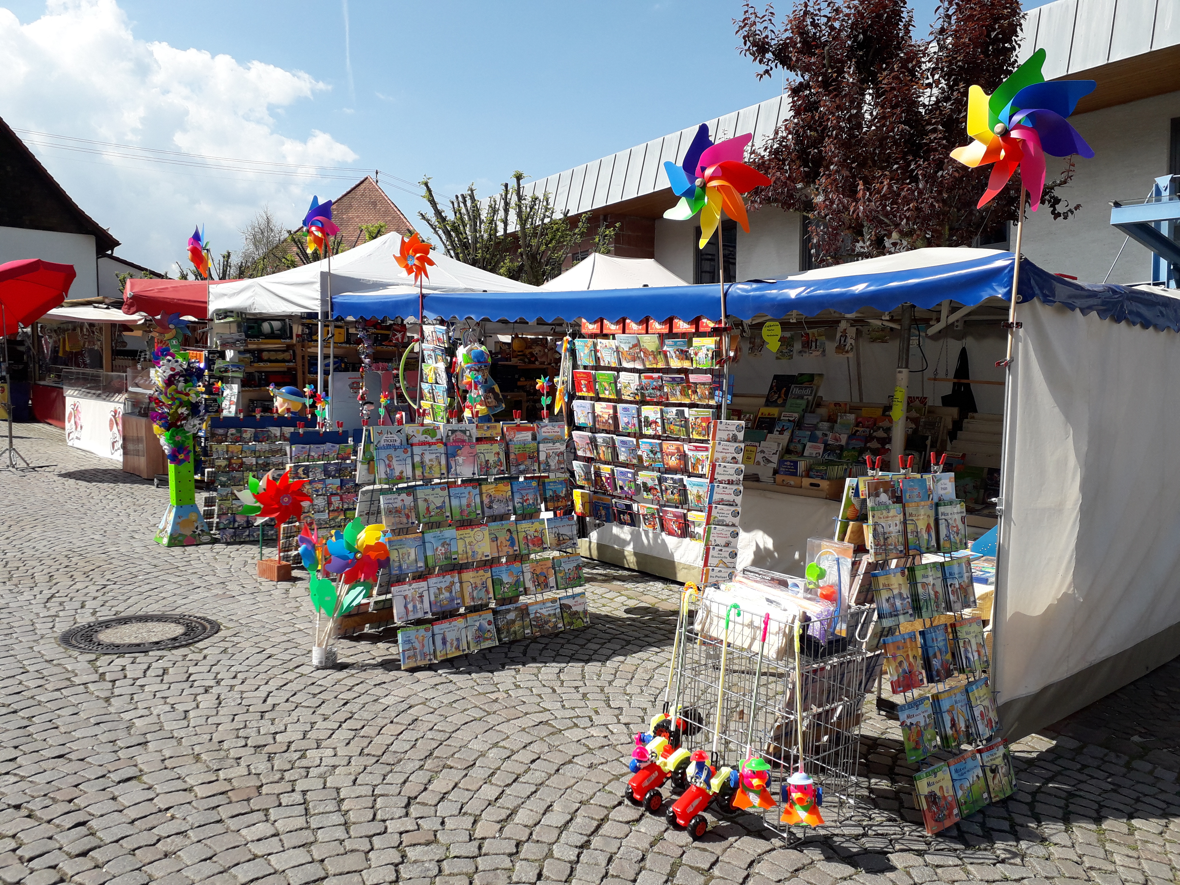Auf diesem Bild Sielwaren und Kinderbücherstand auf dem Maimarkt vor der Kelter um die Gemeindehalle zu sehen.